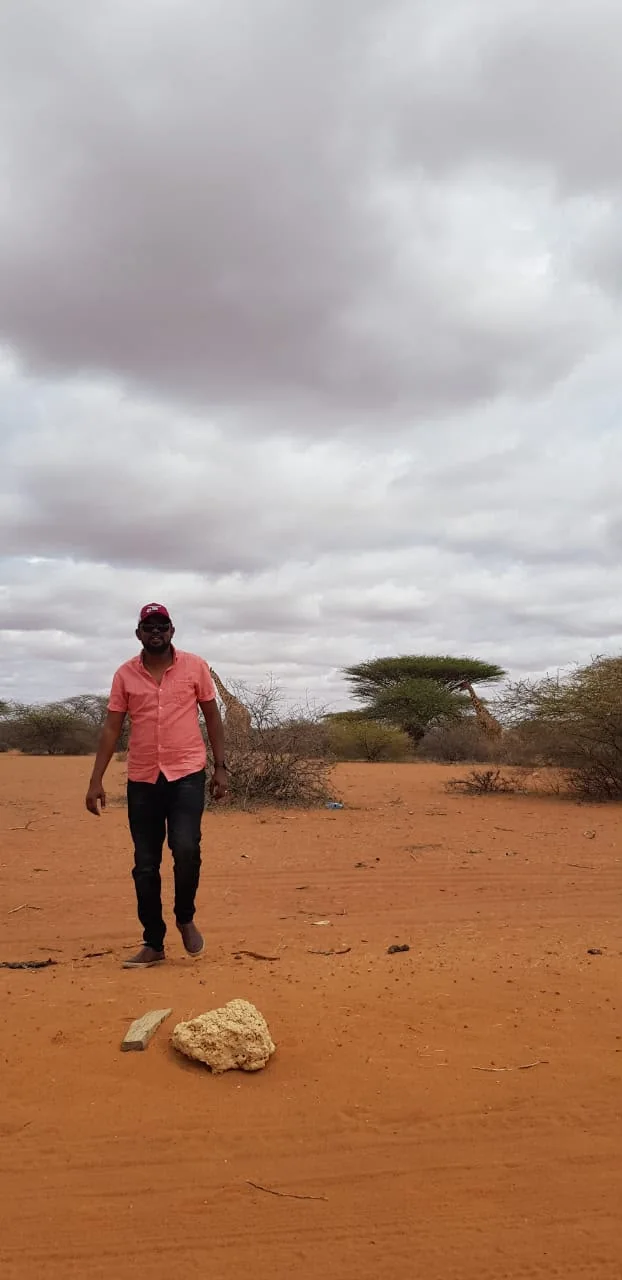 WWCLA CEO walking through a dryland conservancy landscape with giraffes nearby